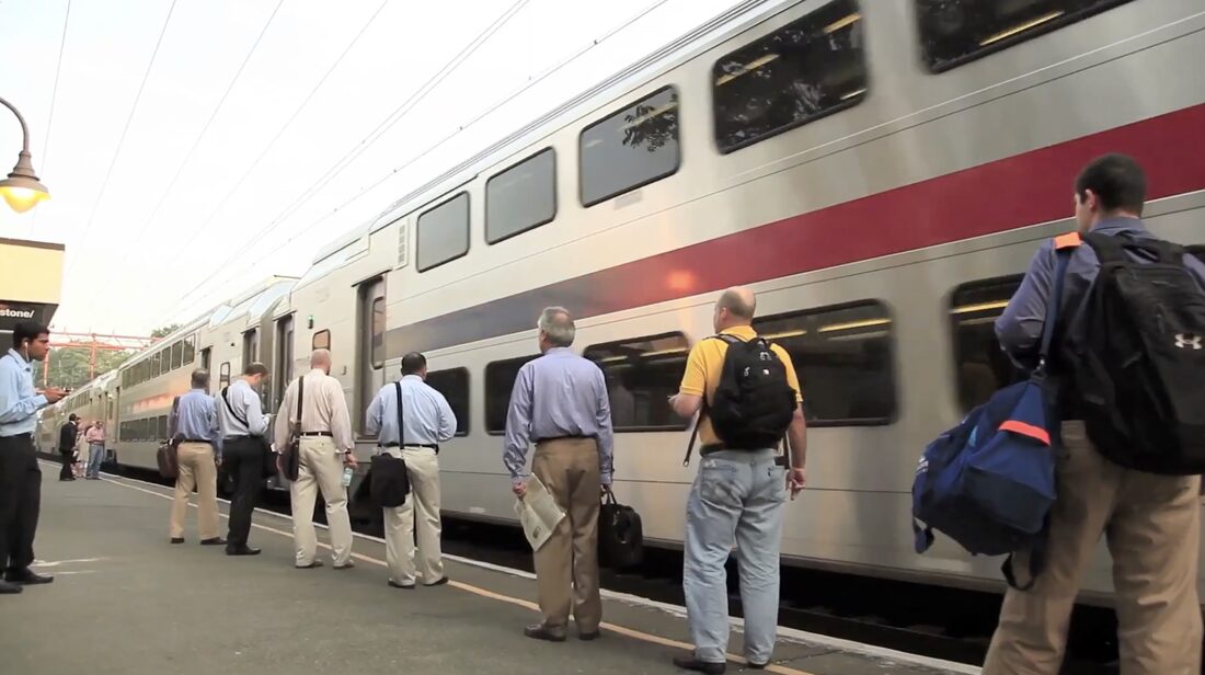 Commuters with bags waiting alongside a train at Millburn Station
